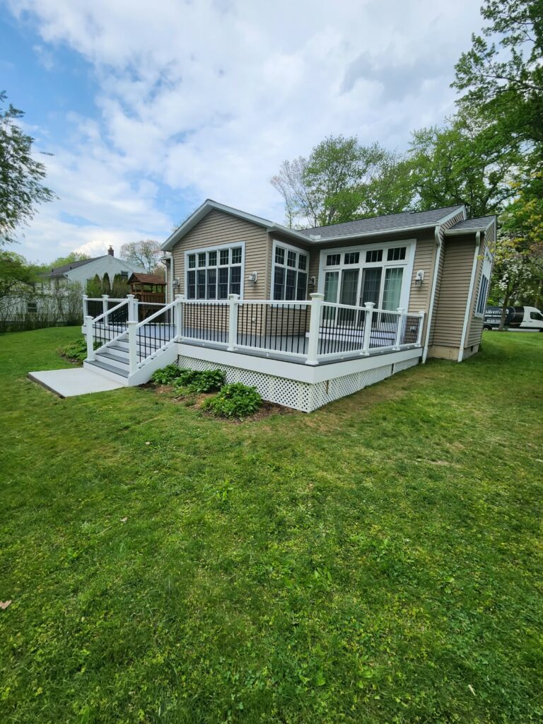 Completed residential deck with black metal railings, white lattice skirting, and stairs